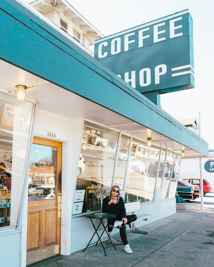 a woman sitting on a chair in front of a coffee shop