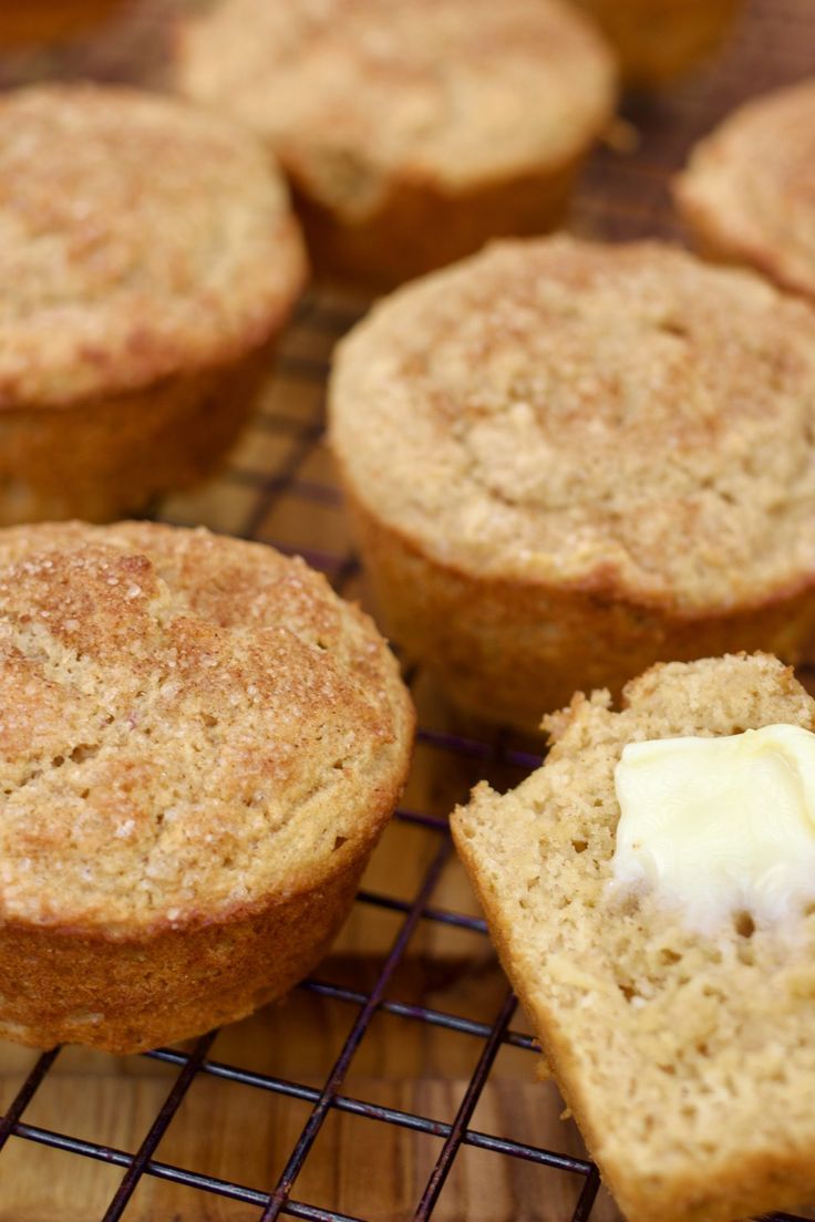 several muffins cooling on a wire rack with butter and cream in the middle