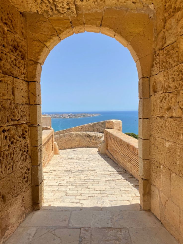 an archway leading to the ocean from a stone building