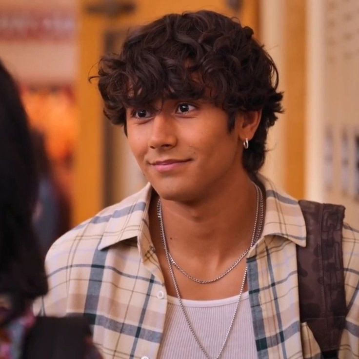 a close up of a person wearing a shirt and necklace with a smile on his face