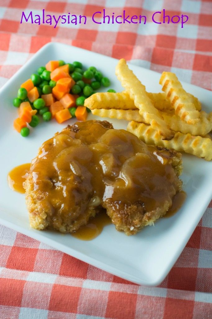 a white plate topped with meat covered in gravy next to veggies