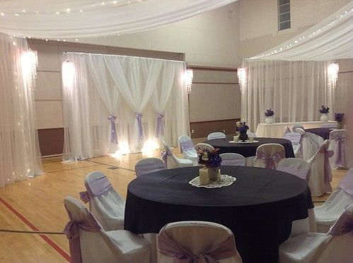 the banquet hall is decorated with white drapes and purple sashes, as well as black table cloths