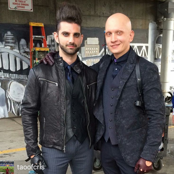 two men standing next to each other in front of a building