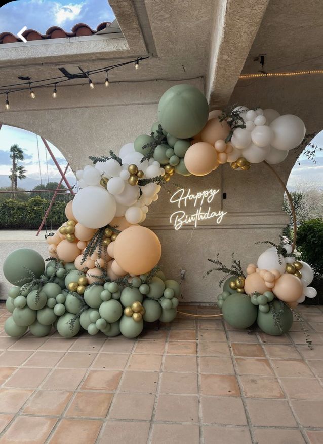 balloons and greenery decorate the entrance to a birthday party