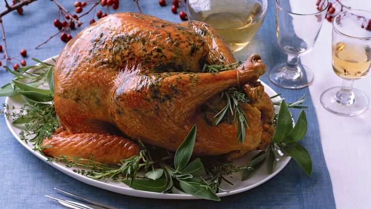 a turkey is sitting on a plate with wine glasses and silverware in the background