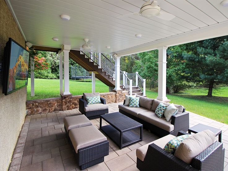 an outdoor living area with couches, tables and stairs on the side of the house