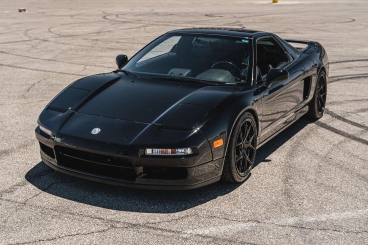 a black sports car parked in an empty parking lot