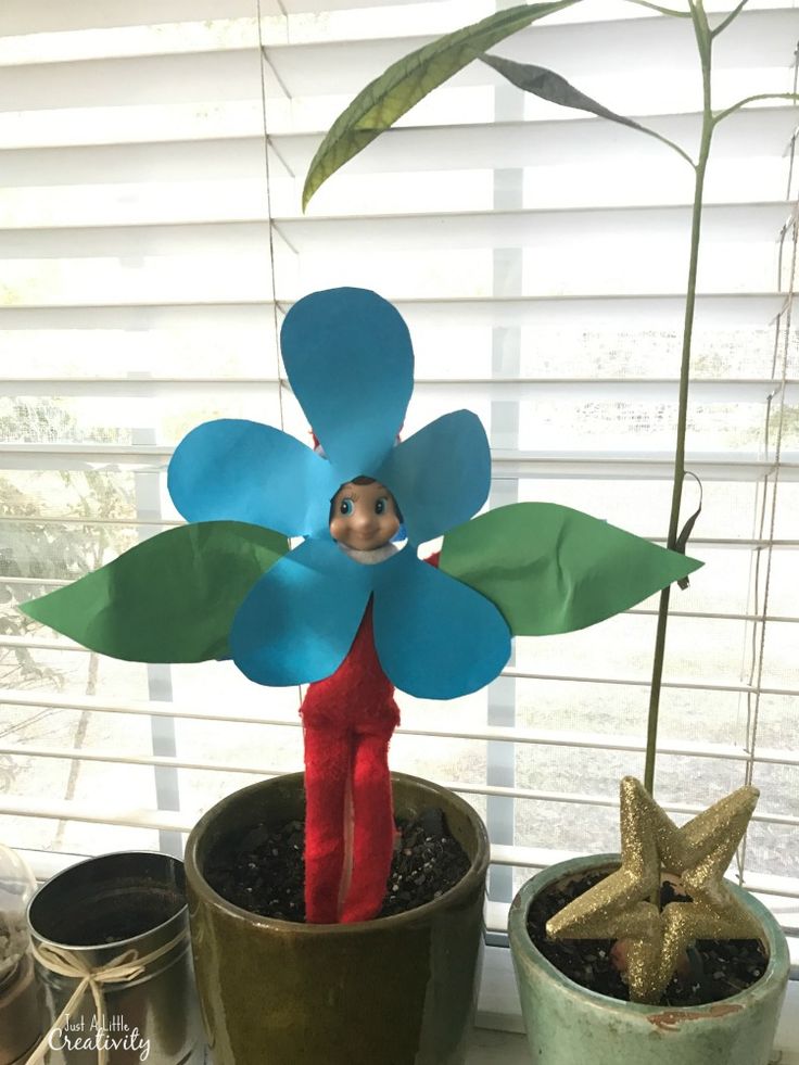 a child's handmade paper flower is shown in front of two potted plants