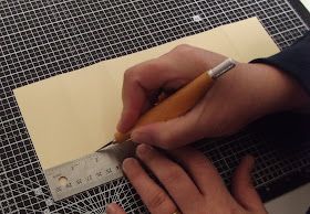 a person using a ruler to cut paper