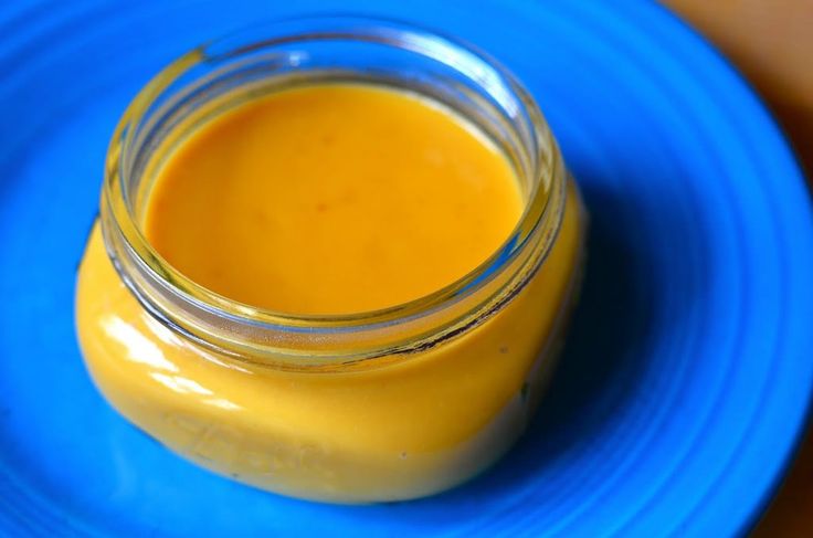 a glass jar filled with yellow liquid sitting on top of a blue plate