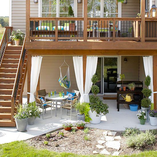 a patio with chairs, tables and plants on the side of it next to a house