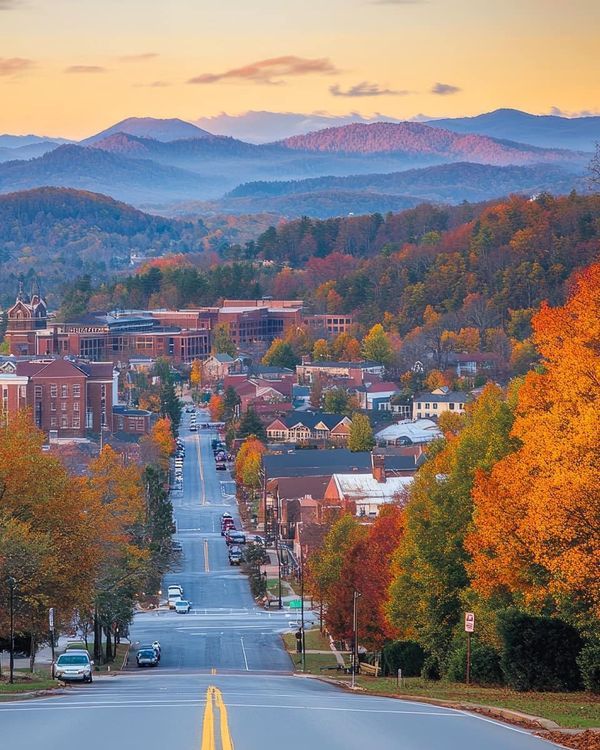 an empty street in the middle of a town with mountains in the background at sunset