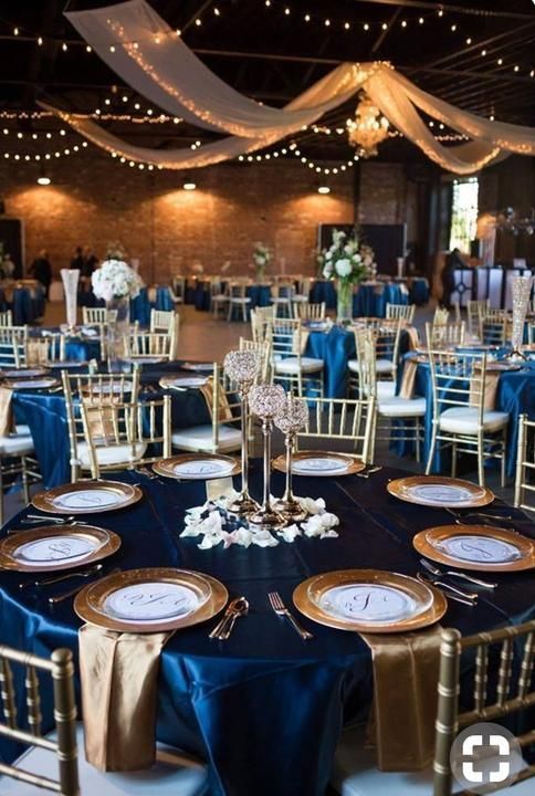 the tables are set up with blue linens and gold chargers for centerpieces