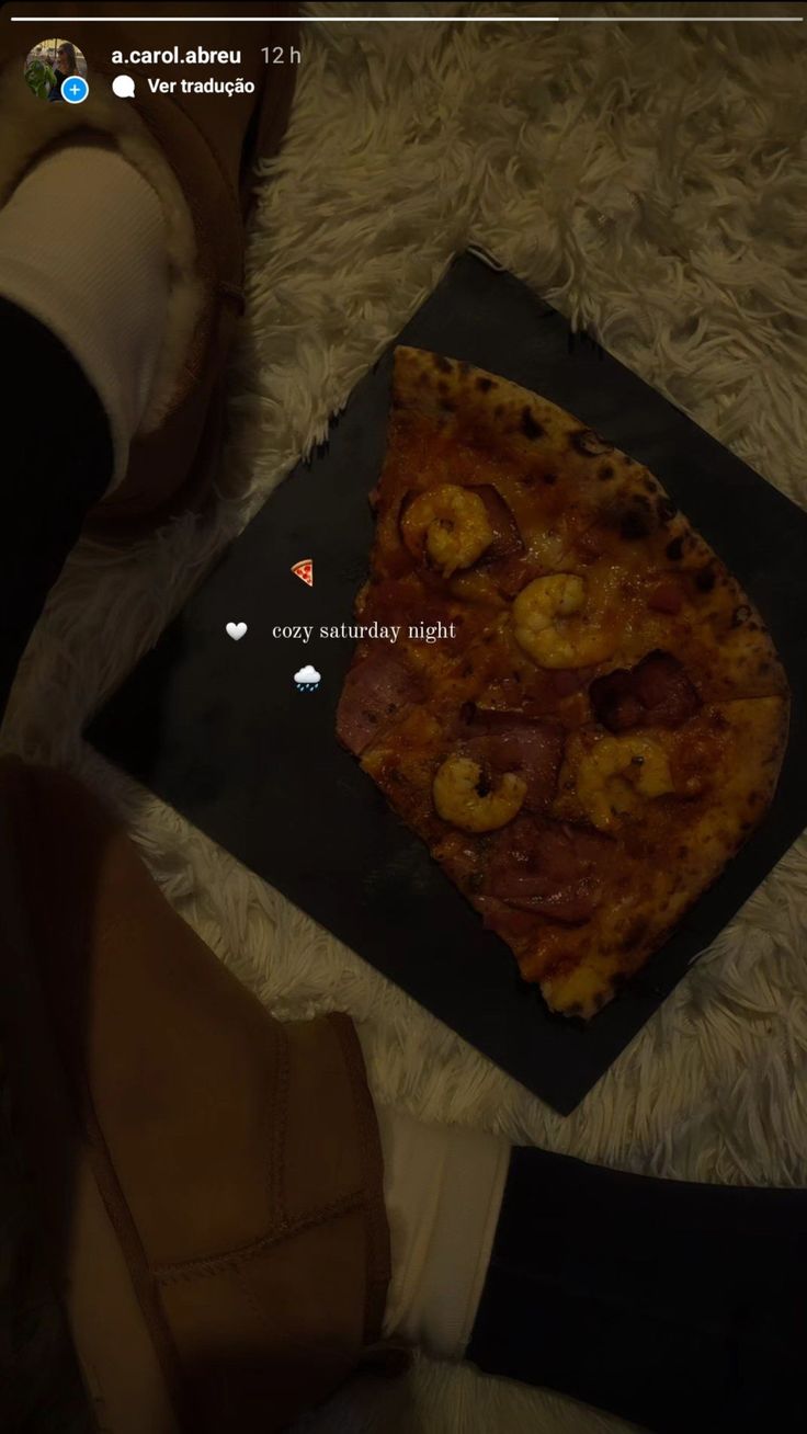 a slice of pizza sitting on top of a black plate next to someone's feet