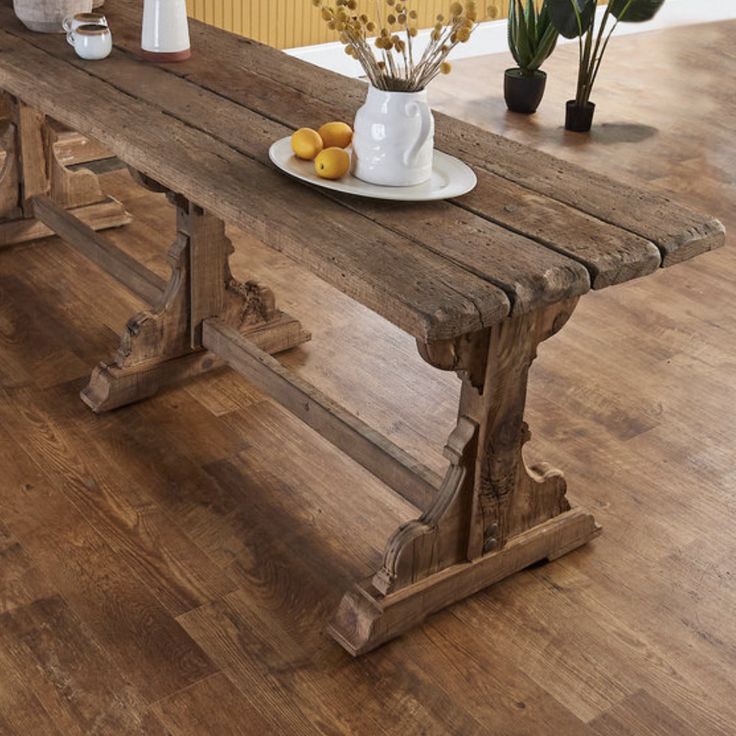 a wooden table with two vases and some lemons on the plate next to it