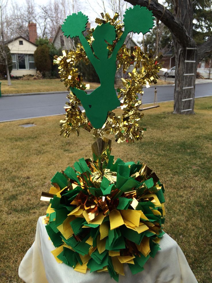 a green and gold decoration on top of a white table cloth in front of a tree