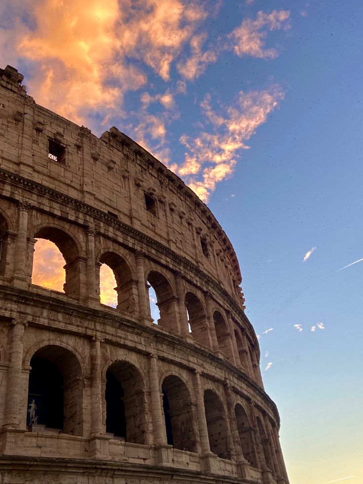 the sun is setting behind an ancient roman structure