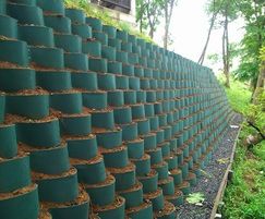 a wall made out of green plastic cups with dirt in the middle and grass growing on top