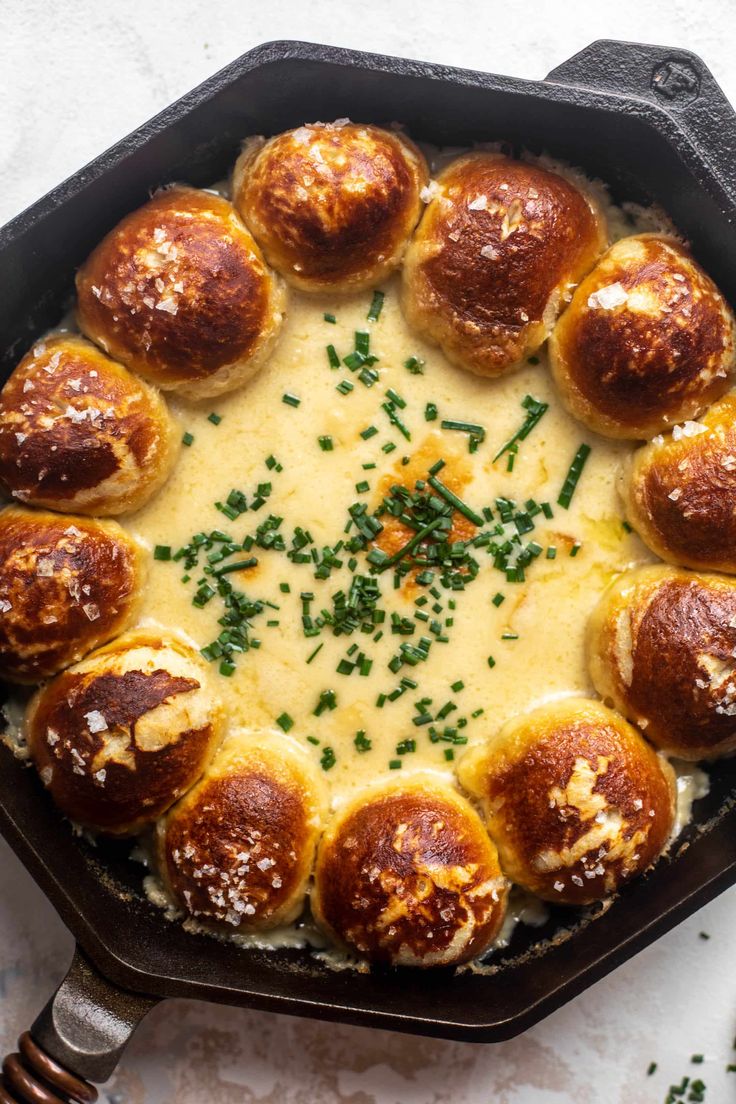 a cast iron skillet filled with cheese and meatball rolls covered in parmesan sauce