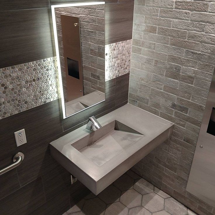 a bathroom with a sink, mirror and towel dispenser