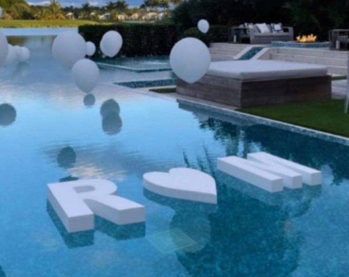 an outdoor swimming pool with floating white balloons