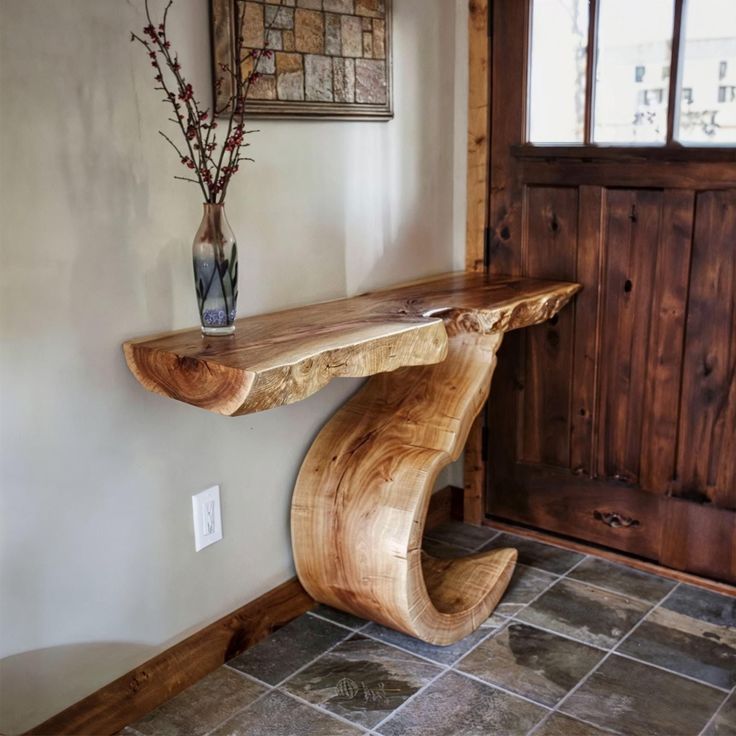 a wooden bench sitting in front of a door next to a vase with flowers on it