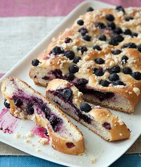 blueberry bread is cut into slices on a white plate with a pink and blue table cloth