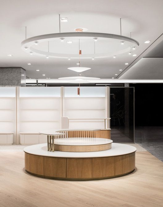 an empty room with round wooden table and white partitions on the wall behind it