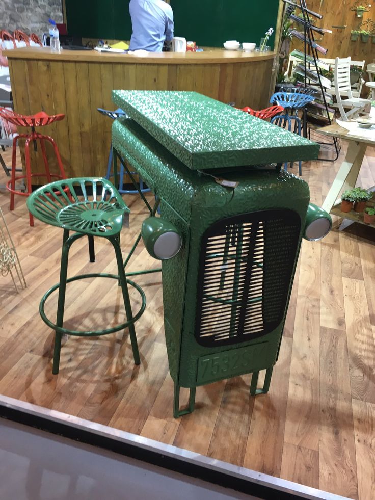 a green table and two stools in a room with wood flooring on the ground