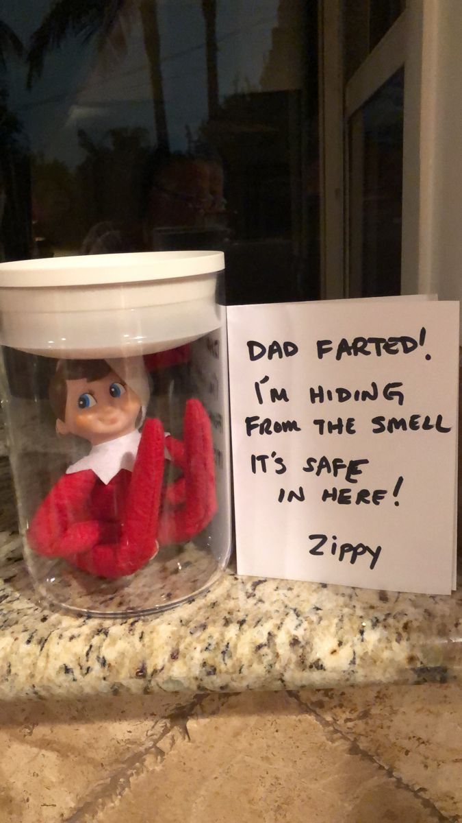 a glass jar with an elf in it next to a sign that says, dad farted i'm hiding from the smell it's safe in here