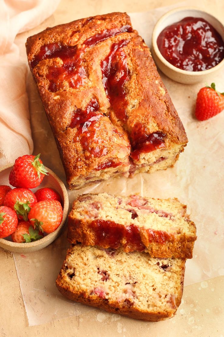 sliced loaf of strawberry bread next to bowl of strawberries