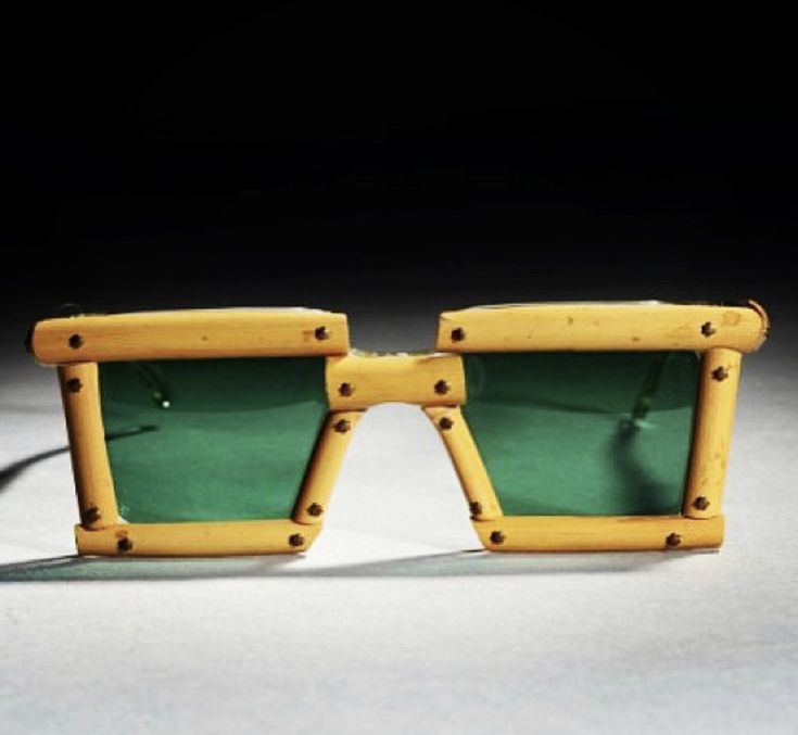 a pair of sunglasses with wooden frames and green tinted lenses on a white surface in front of a black background