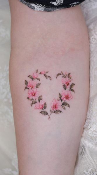 a woman's thigh with pink flowers in the shape of a heart