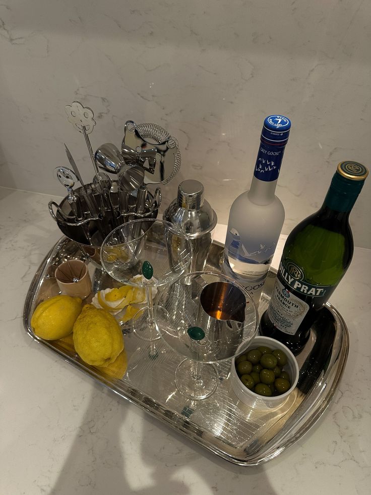 an assortment of wine, olives and other condiments on a silver tray