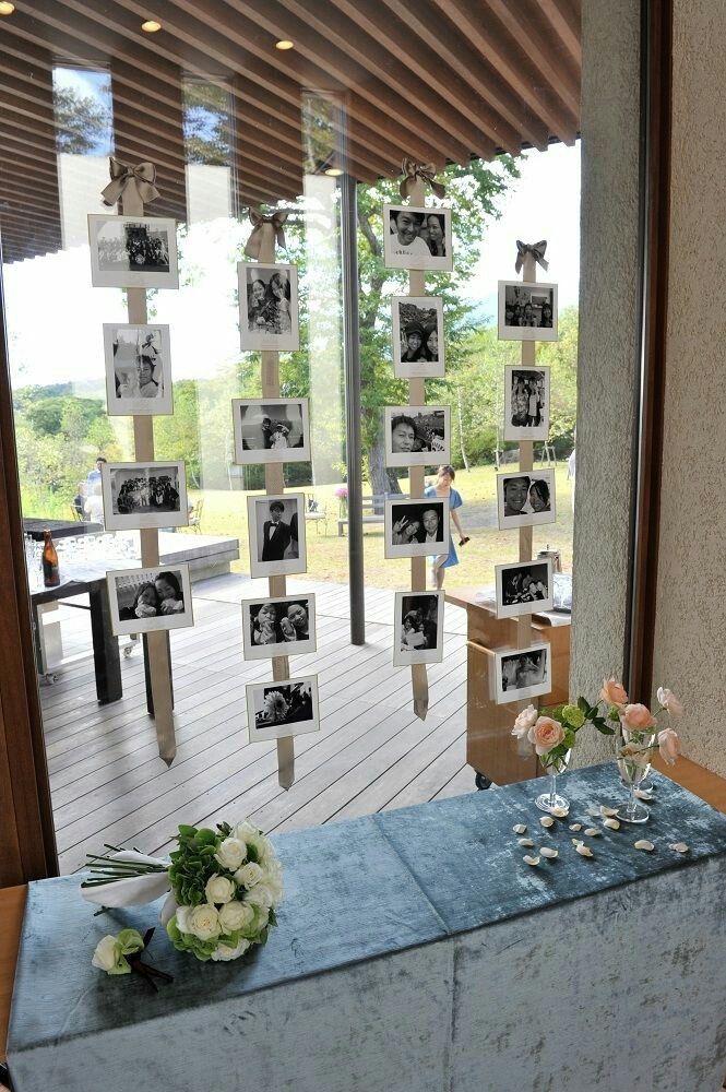 a table with flowers and pictures on it in front of a glass door that is open