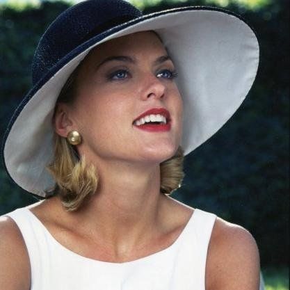 a woman wearing a white dress and blue hat with her eyes closed, looking to the side