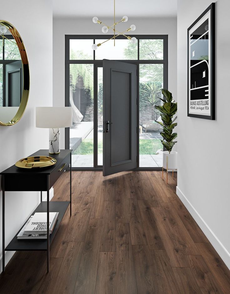 an entryway with wooden floors and white walls, large glass doors to the outside