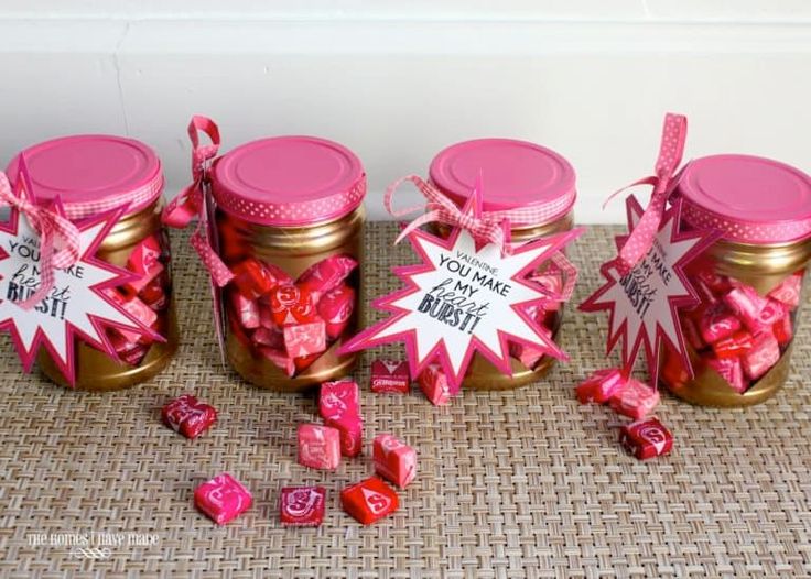 three jars filled with pink and white candy sitting on top of a table next to each other