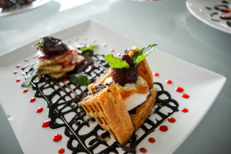 three desserts on a white plate with sauce and garnishes around them