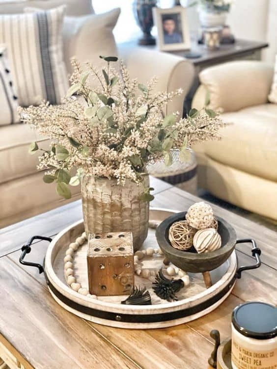 a tray with some flowers and other things on it sitting on a coffee table in a living room