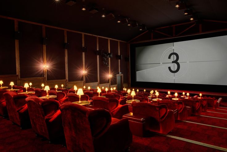 an empty movie theater with red chairs and candles lit up in front of the screen