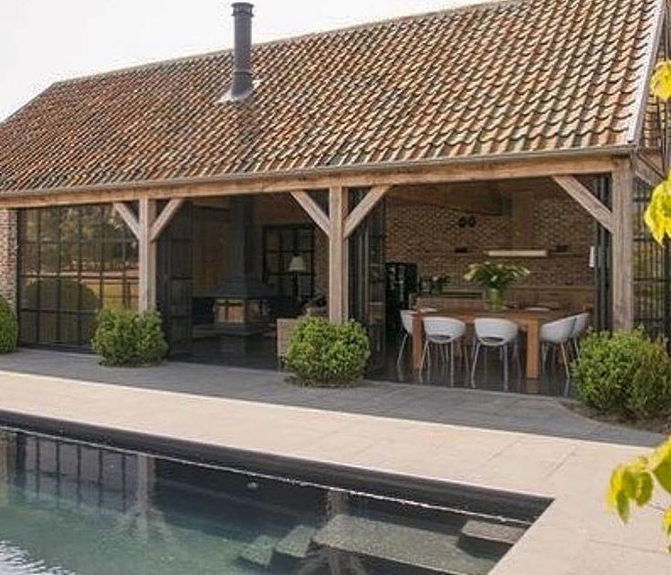 an outdoor dining area next to a pool in the middle of a garden with potted plants