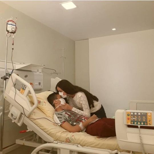 two people in a hospital bed with an iv machine