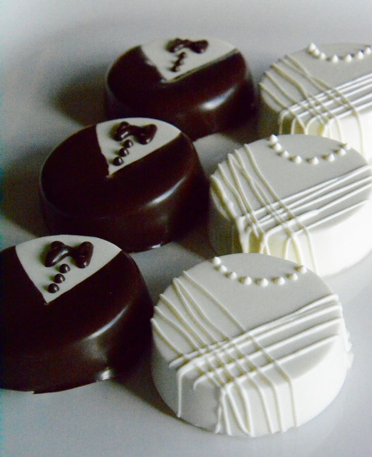 four pieces of chocolate covered in white and brown icing with designs on them sitting next to each other