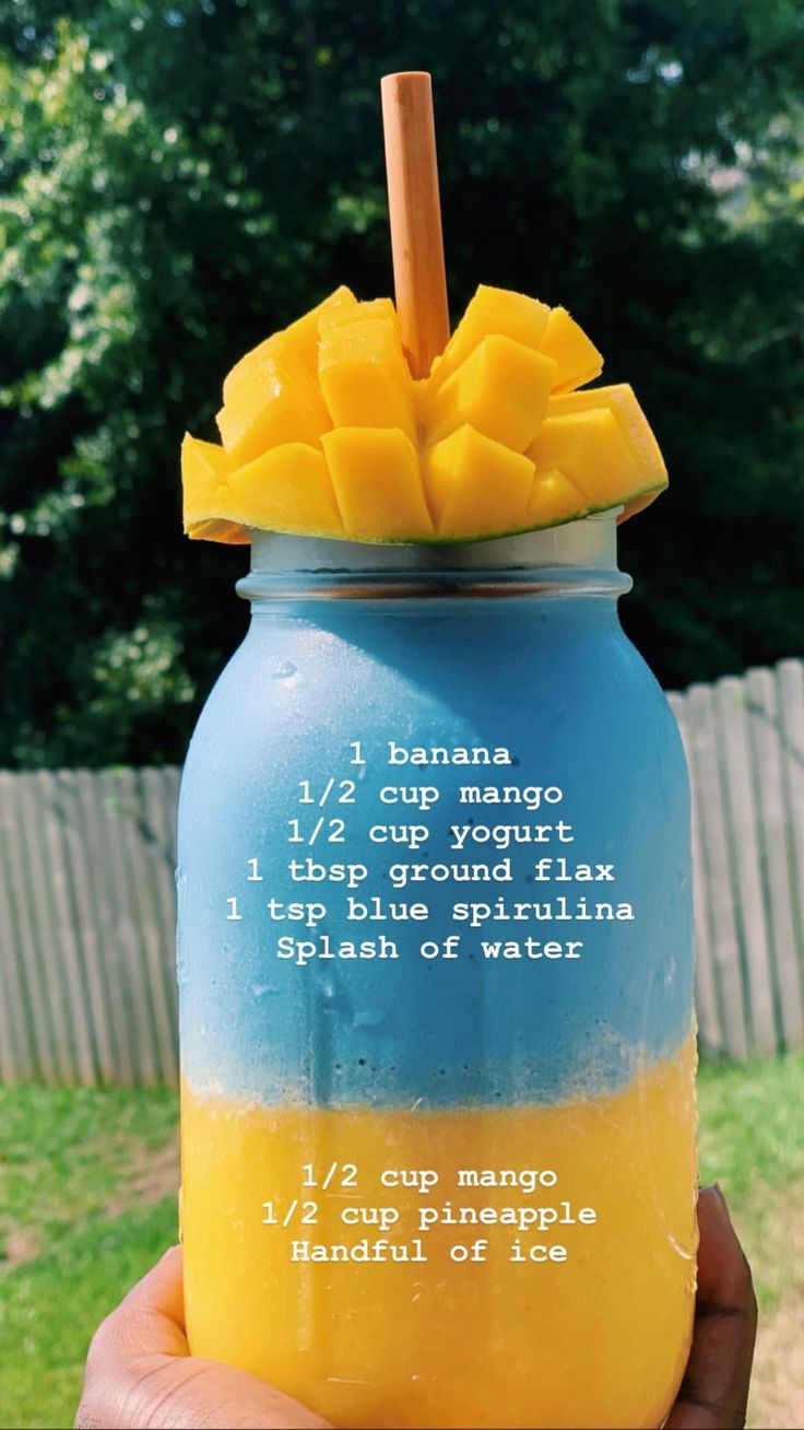 a hand holding a blue and yellow mason jar with pineapple on top, labeled 1 / 2 cup mango