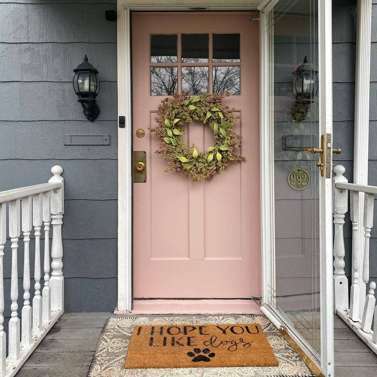 a pink front door with a welcome mat on it