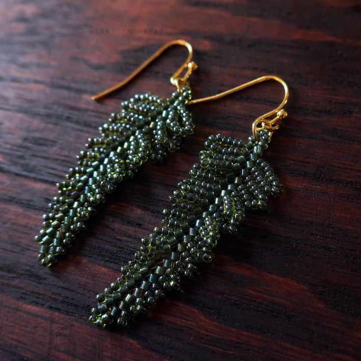 green beaded earrings sitting on top of a wooden table