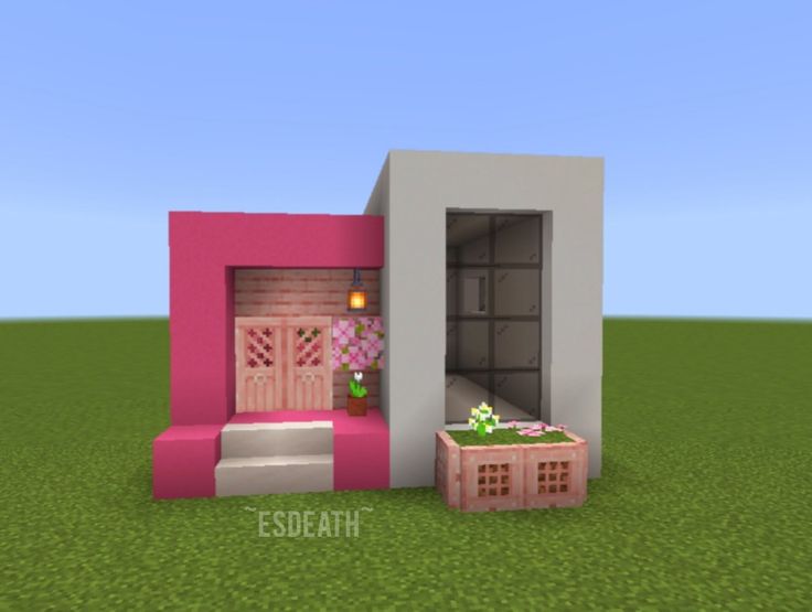 a small pink house sitting on top of a lush green field next to a door