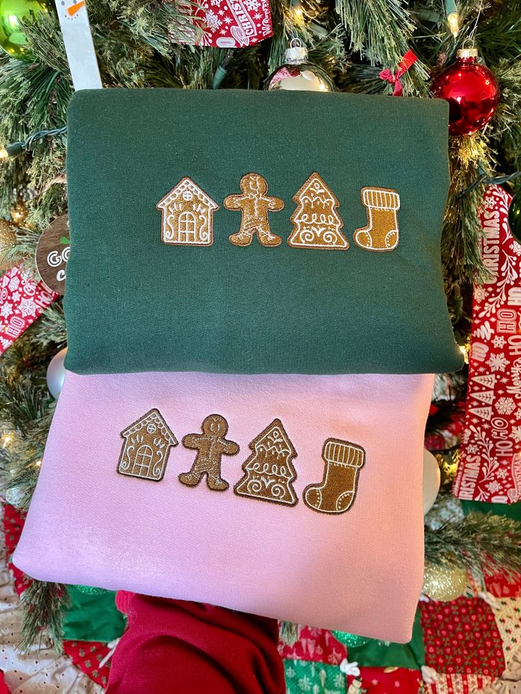 three different colored christmas stockings with gingerbreads and houses on them in front of a christmas tree