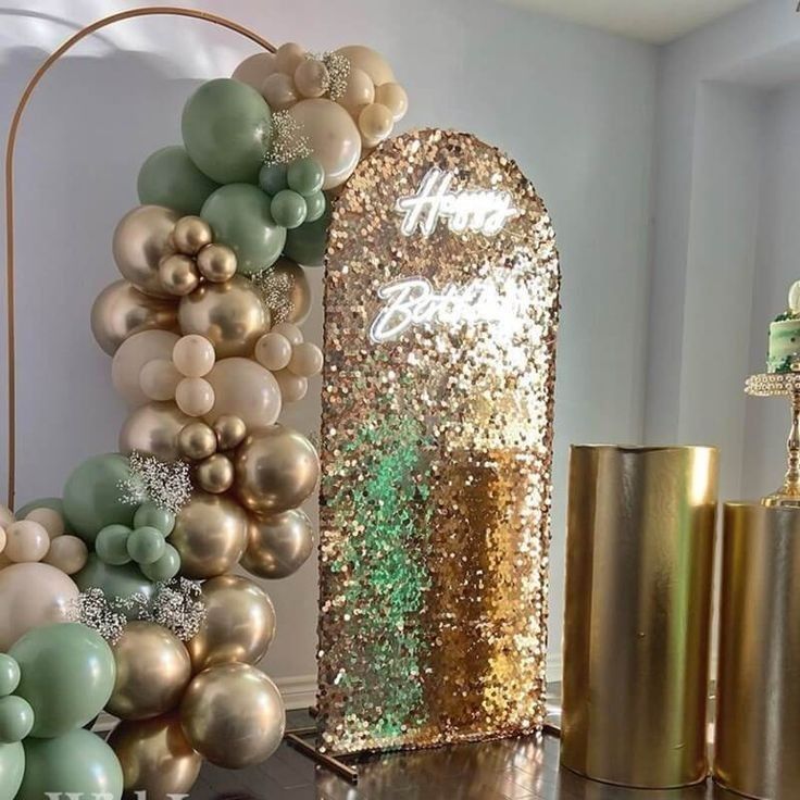 some gold and green balloons are on a table next to two vases with flowers